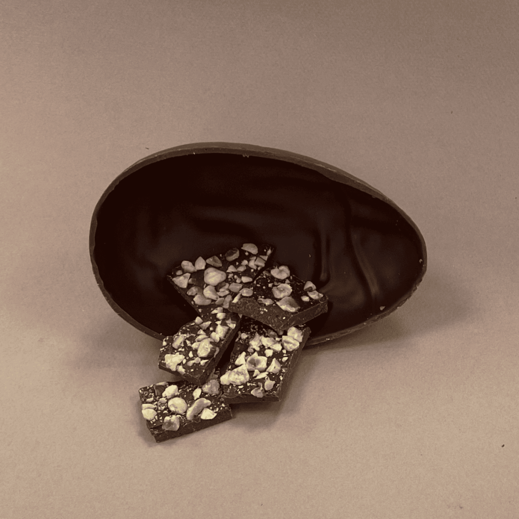 Oeuf de Pâques au chocolat au lait ouvert avec des plaques de chocolat noisette à l'intérieur