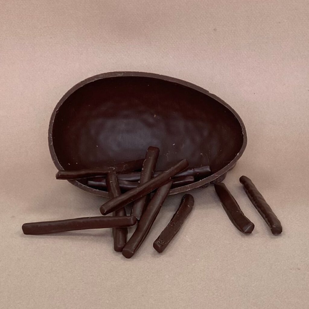 Oeuf de Pâques au chocolat noir ouvert avec des orangettes à l'intérieur